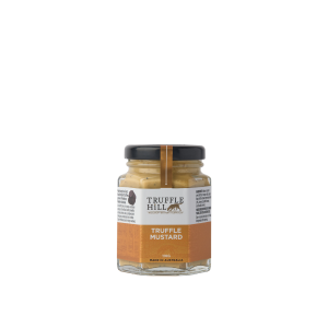 A hexagonal glass jar with a black label branded Truffle Hill. Label describes Truffle Mustard